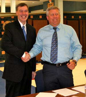 David Hamilton (left) and Jeff Morehouse, president of the Penn Yan School Board of Education shake hands after signing Hamilton’s contract.