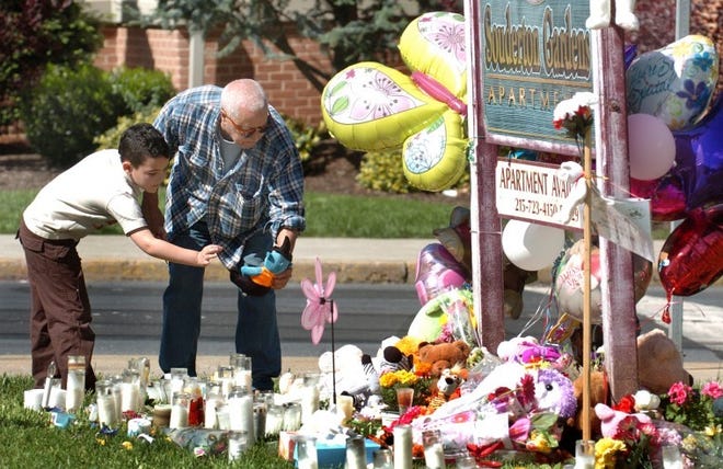 Six-year-old Jaden Parks and his grandfather, Pau Camacho, (Telford), lay a stuffed animal on the makeshift memorial to Skyler Kauffman on Wednesday.