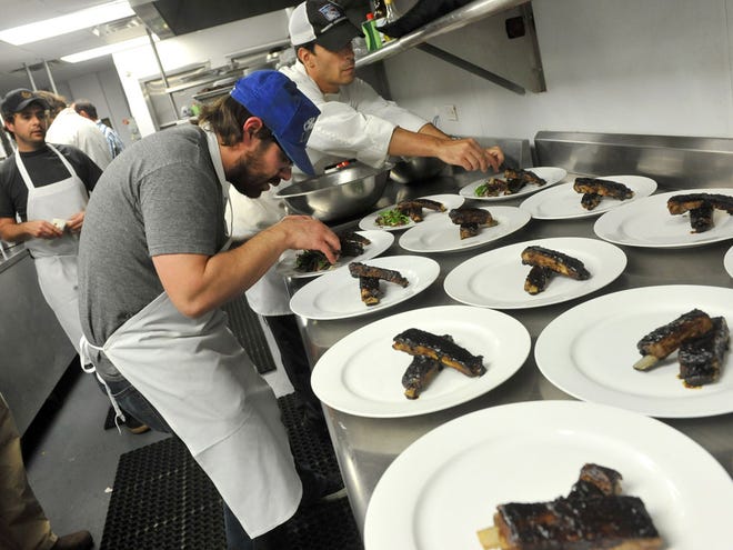 This April 29 photo shows chef Vinny Dotolo, center, of Animal House and Son of a Gun restaurants in Los Angeles, as he prepares a rib dish for the JBF LTD pop-up restaurant in New York, while chef Jon Shook, far left, looks on. (AP Photo/Diane Bondareff)