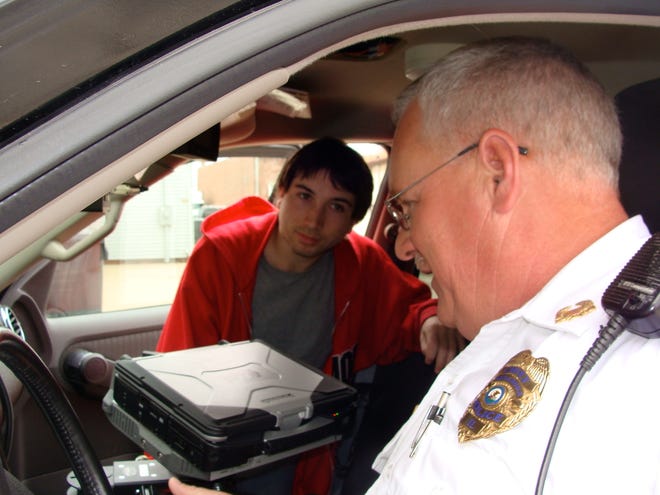 Metamora Police Chief Mike Todd, in foreground, explains the technology in his police vehicle to MTHS senior Gage Turner, 18. Todd says if changes made by the Metamora Village Board to his manpower structure put the concept of community policing at risk in the village.