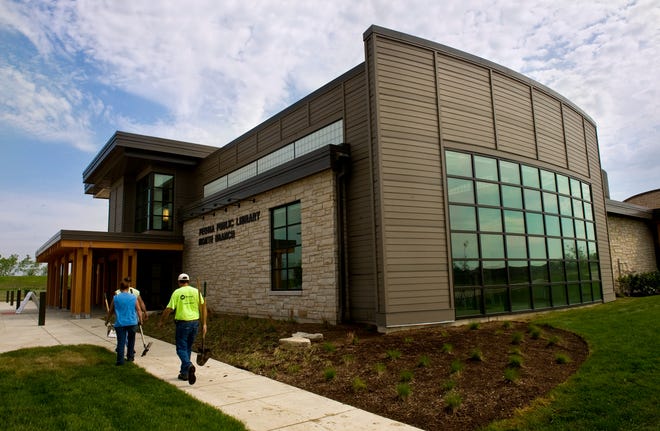 Workers and library staff make final adjustments as the new Peoria Public Library North Branch prepares for an open house. The exterior of the 30,000-square-foot facility includes a prairie savanna landscape, environmentally sensitive bioswales, and walking trails through the Illinois native plant landscape. The new branch sits at an angle on the property, its back to Illinois Route 6, from which it can be seen but not accessed. The library is located on a road behind Menards off Allen Road.