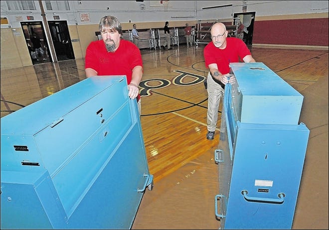 Voters will decide on budgets and board candidates Tuesday in the region’s 34 school districts. Port Jervis Middle School custodians Tony Woolsey, left, and Ray McBride roll voting machines into place Monday.