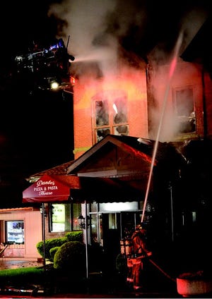 New Philadelphia fire department ladder team sprays the upper floors of Dante's Pizza and Pasta House while supporting personnel works from the ground level between 3:30 to 4am Monday.