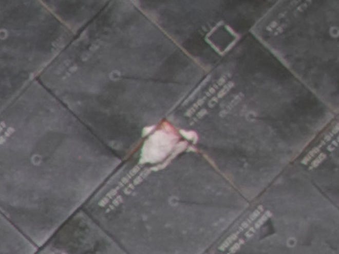 This image made available by NASA on Friday, May 20, 2011, shows a damaged thermal tile on the space shuttle Endeavour's underbelly. The crew is planning to use a laser-tipped boom early Saturday to inspect the gouge, which is about the size of a deck of cards.