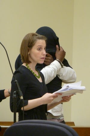 Norman Barnes, 28, of Dorchester, his head covered by a shirt, faces charges he held a 15-year-old girl against her will inside a North Quincy inn on Thursday. In front of him is his lawyer, Joanna Sandman.