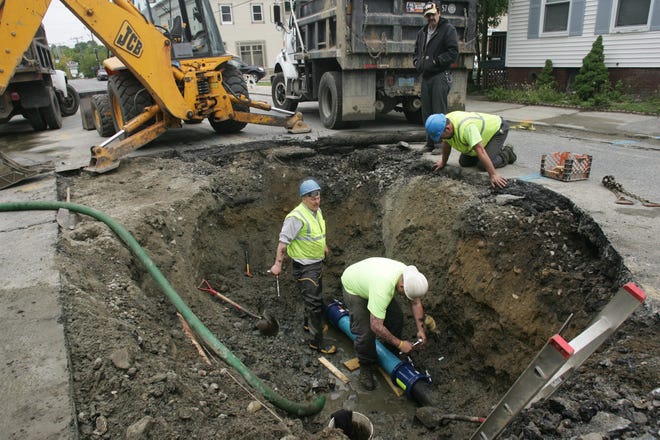 Marlborough DPW workers Rob Armour, in hole at left, and Matt Armour repair a broken water main on Maple Street on Sunday as Keith Bartlett, kneeling, watches.