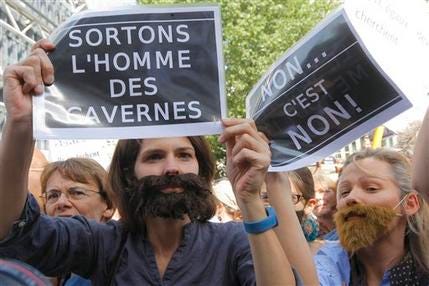 This Sunday, May 22, 2011, file photo shows women holding signs and wearing false beards as they ptotest against sexism, rape and sexual crimes in Paris.