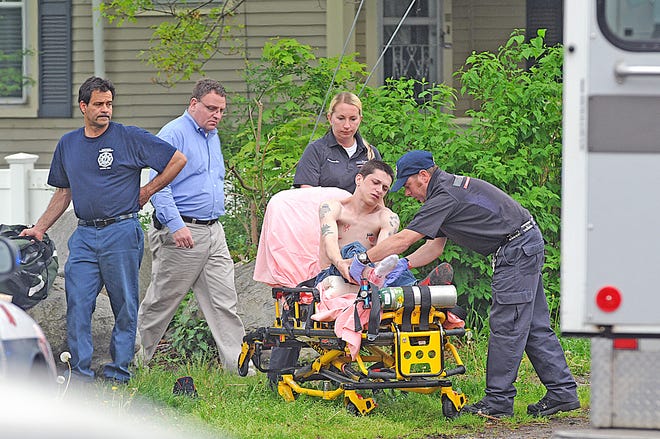 AMR medical personnel prepare the victim for transport. Taunton Police Chief Ed Walsh, center, is at the scene.