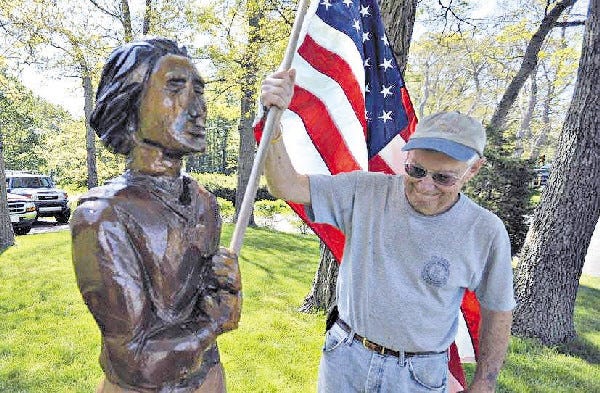 Barry Kavanaugh puts the flag back in the hands of "The Player" after it got fitted for a pair of new legs. The statue was sidelined last year when its ankles rotted out.