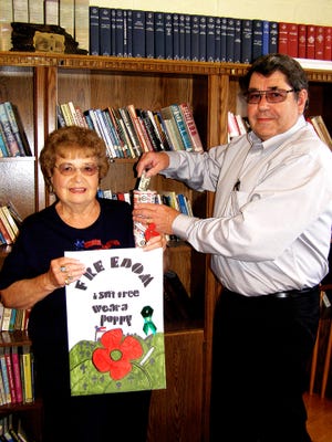 Bess Anderson, president of the Cambridge American Legion Auxiiliary No. 411, offers a puppy to Cambridge mayor James Crouch. Members of the auxiliary will be distribuing poppies Friday and Saturday, May 27 and 28, at businesses throughout Cambridge.