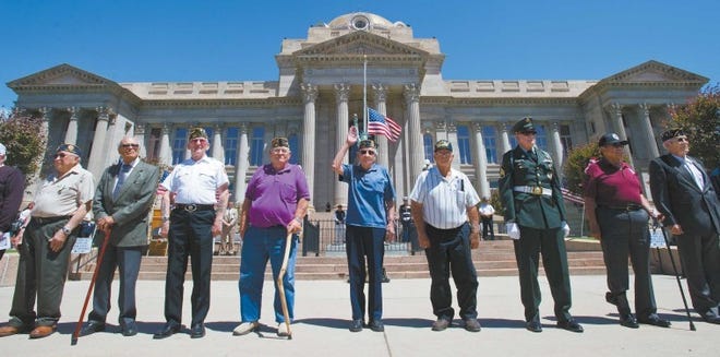 Joe Medina (center) raises his hand during a roll call of Pueblo-area Korean war veterans Monday at the Pueblo County Courthouse. Medina was one of 26 Korean veterans recognized for their service to country at the Pueblo Veterans Council Memorial Day ceremony.