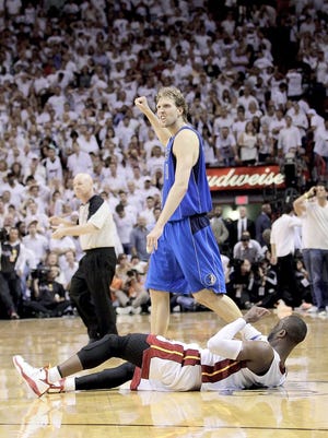 Dallas Mavericks forward Dirk Nowitzki pumps his fist as Miami Heat guard Dwyane Wade falls on the floor at the end of Game 2 of the NBA Finals. By DAVID J. PHILLIP, The Associated Press