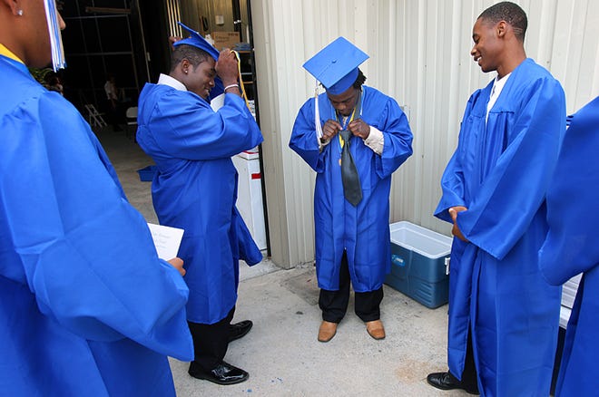 Joe'Von Holman, center, ties De'Vante Hackney's tie, right, before the start of the Pedro Menendez Commencement Ceremony at the St. Augustine Amphitheatre on Saturday morning. 'I ought to charge a buck a tie,' said Holman, who was asked by several classmates to help them out. By DARON DEAN, daron.dean@staugustine.com