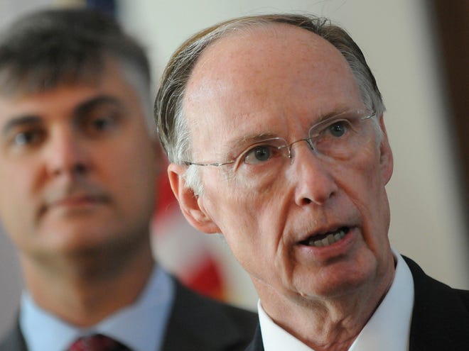 Sen. Scott Beason R-Gardendale, left, listens as Alabama Gov. Robert Bentley speaks before signing into law what critics and supporters are calling the strongest bill in the nation cracking down on illegal immigration, on Thursday at the state Capitol in Montgomery.