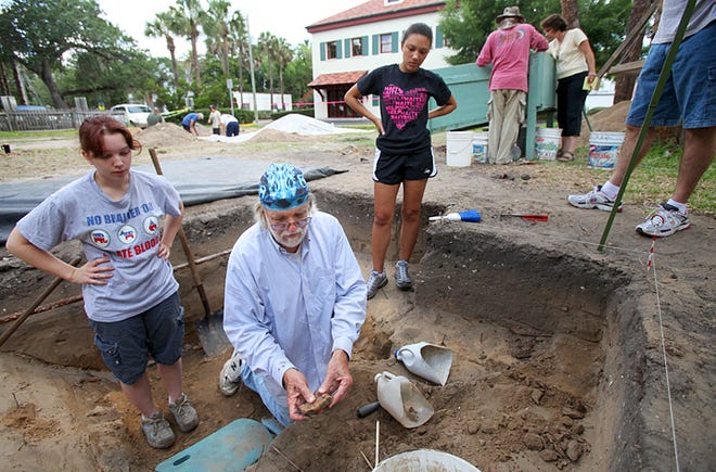 City Archaeologist Carl Halbirt examines a radius bone from a cow that was uncovered in a trash pit dating to the British Period as Flagler College students Sarah Norrie, left, and Merika Childers look on during an excavation at 63 Cordova St. last week. By DARON DEAN, daron.dean@staugustine.com