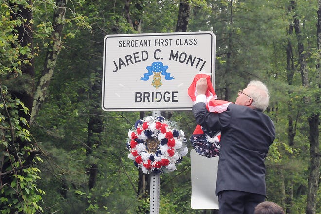 Paul Monti, father of Raynham Medal of Honor recipient Army Sgt. 1st Class Jared C. Monti, unveils a sign on the bridge dedicated in memory of his late son on Sunday.