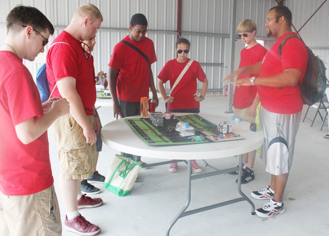 Several ACE students review a model airport while standing in an airplane hanger at Louisiana Regional Airport. Red shirts were the signature style of each camp member, including instructors.
