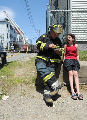 Brockton Fire Lt. Eddie Williams talks with Kayla Lamb, 10, of Brockton, who was home alone when the fire started at her house at 10 Baxendale Ave. in Brockton on Tuesday, June 21, 2011.