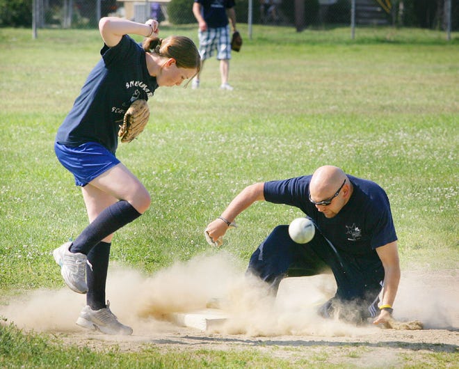 Marshall teacher Micah Siegel slides safely into third as Snug Harbor third baseman and teacher Mary Bloomer avoids his slide during a friendly softball game Tuesday in Quincy to raise money for disaster relief.