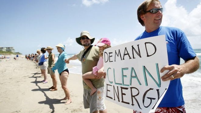 Kenneth Montgomery holds his daughter Abby, 5, next to Frank Tobias, right, of Palm Beach Gardens, as they join about 50 people in the second Hands Across the Sand offshore oil drilling protest at Carlin Park in Jupiter on Saturday, June 26, 2010.