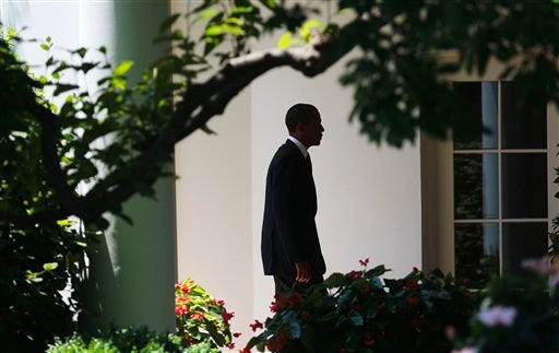 A silhouetted President Barack Obama walks back to the Oval Office of the White House in Washington, Friday, June, 24, 2011, following his arrival on Marine One helicopter.