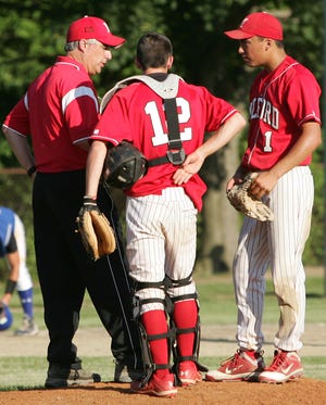 Longtime Milford baseball and basketball coach Steve Manguso (left), shown this spring making a pitching change, favors the Scarlet Hawks' move to the Hockomock League.