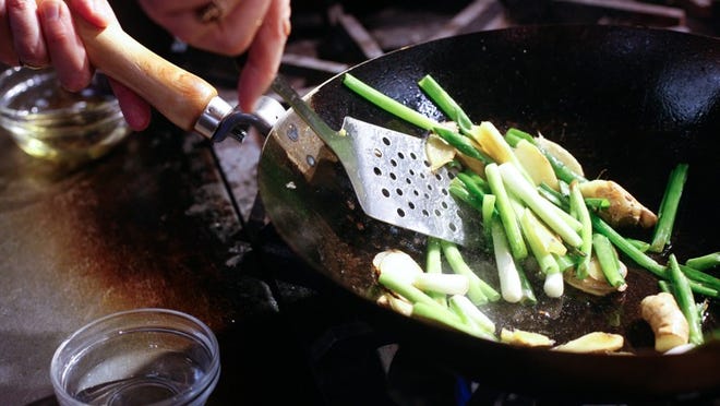 A carbon steel wok is an inexpensive and effective tool for the kitchen or backyard, and cooking in one starts with seasoning the pan with oil, ginger and scallions.