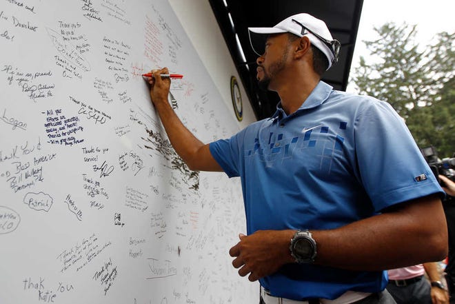 Tiger Woods signs a We Salute Our Heroes tribute wall on Tuesday at Aronimink Golf Club in Newtown Square, Pa. Woods says he's done playing with pain, and he will return to the PGA Tour only when he's healthy.