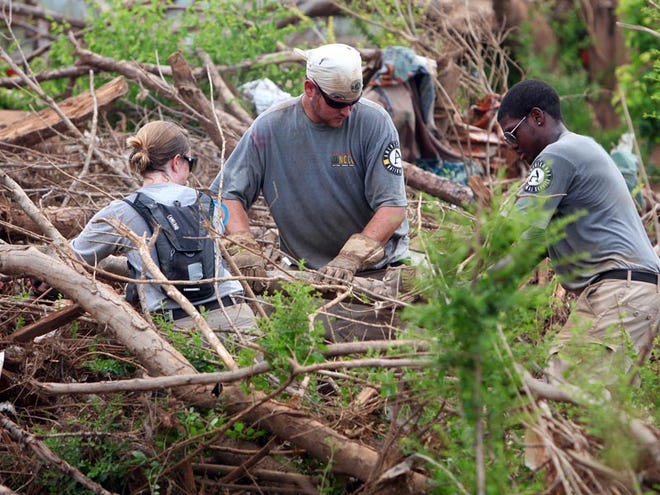 AmeriCorps volunteers, from left, Emma McAuley, Greg Malbon and David Winston remove debris in Holt on Tuesday.