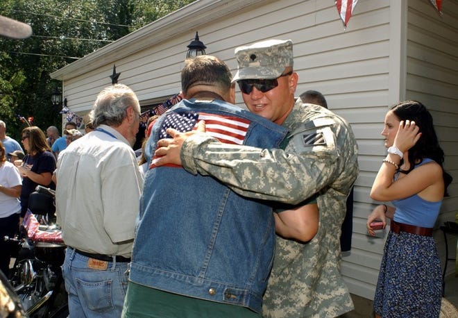 Specialist Michael Forgash, Jr. (facing), an Army medic, gets a
hug from Bob Flamard (of Camden, a member of Warriors Watch
Riders), as he is welcomed home to 17 Saxony Drive in Cinnaminson
after serving a year in Iraq. At right is Michael's girlfriend
Megan Gertie (of Cinnaminson).