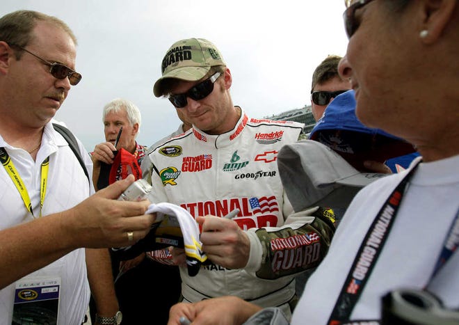 Dale Earnhardt Jr., center, signs autographs for fans after his qualifying run for the NASCAR Coke Zero auto race at Daytona International Speedway in Daytona Beach, Fla., Friday, July 1, 2011. (AP Photo/John Raoux)