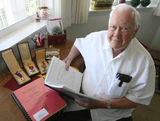 World War II veteran Bob McLeay thumbs through one of two books about the 1255th Combat Engineers battalion, the U.S. Army unit in which he served. McLeay received the Purple Heart, Bronze Star and other medals during the Battle of the Bulge.