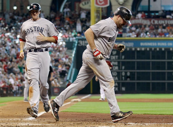 The Red Sox's Kevin Youkilis, right, heads toward first base after being walked with the bases loaded as Drew Sutton, left, advances from third to home to score a run during the ninth inning of Sunday's interleague game in Houston.