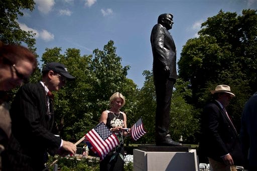 People take their turn to pose for photographs beside a statue of the late U.S. President Ronald Reagan after its unveiling outside the U.S. embassy in London, Monday, July 4, 2011. The 10 foot bronze was unveiled Monday to mark the centenary of Reagan's birth. (AP Photo/Matt Dunham)