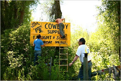 Del Lockhart and his sons, Dawson and Jonathan, repainting signs along Route 40 that advertise the F. M. Light & Sons clothing store.
