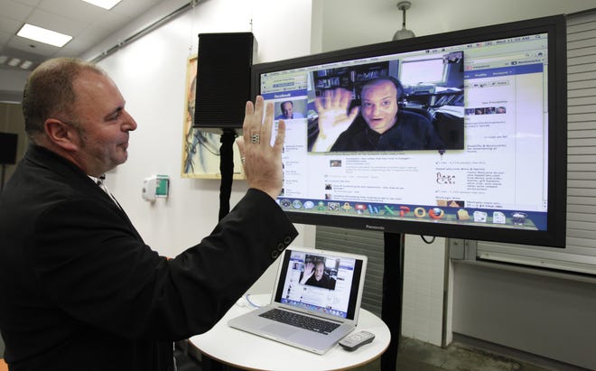 Facebook workers Mike Barnes, left, Video Chats with Jonathan Rosenberg, right, on Facebook during an announcement at Facebook headquarters in Palo Alto, Calif., Wednesday, July 6, 2011. (AP Photo/Paul Sakuma)