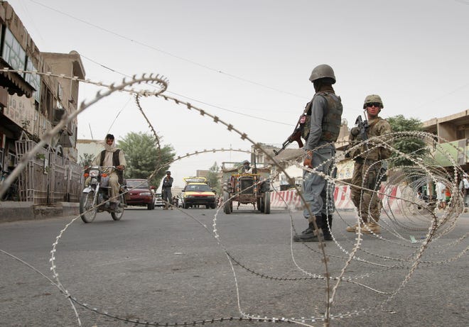 A U.S. soldier, right, is seen with an Afghan police officer during a searching for a missing British soldier at a check post in Kandahar, Afghanistan Monday, July 4, 2011.