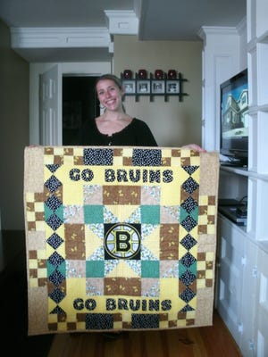 Kate McCullough holds a Bruins quilt