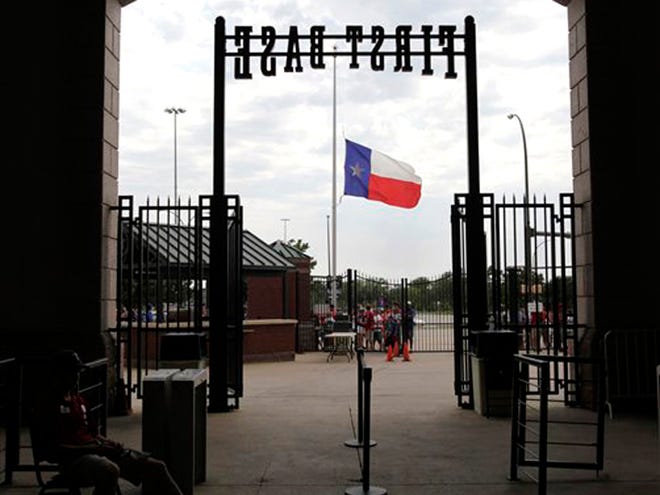 A Texas Rangers ballpark employee sits waiting for the gates to open as fans stand by a Texas flag the sits at half staff before the start of a baseball game against the Oakland Athletics Saturday, July 9 in Arlington, Texas.