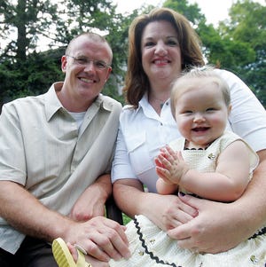 Photo by Daniel Freel/New Jersey Herald 
Mike and Carolyn Ryder pose for a photo with their adopted daughter, Ella, outside their Franklin home Tuesday. For Ella’s first birthday, the couple is asking that, instead of gifts, all of their guests bring food to be donated to the pantry at Catholic Family and Community Services, Partnership for Social Services in Franklin.