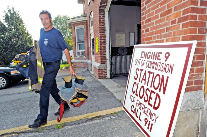 Taunton firefighter Tim Moreau carries his coat, boots and helmet to his car as he leaves the East Taunton station on Middleboro Avenue in preparation for his re-assignment to the Bay Street station for Monday’s night shift.