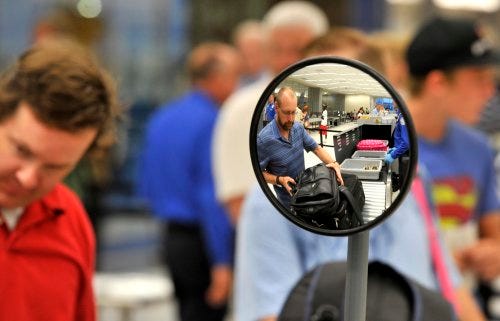 Passenger Terry Rossi, reflected in mirror, places his carry-on bags in the TSA screening area Tuesday at the new terminal in Rick Husband Amarillo International Airport.