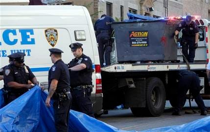 Police officers prepare to remove a dumpster, right, that is part of an investigation about a missing 8-year old boy in the Brooklyn borough of New York, Wednesday, July 13, 2011. Remains believed to be those of Leiby Kletzy, 8, who disappeared while walking home from a Brooklyn day camp were found in a refrigerator Wednesday inside the home of a man being questioned by detectives, police said.