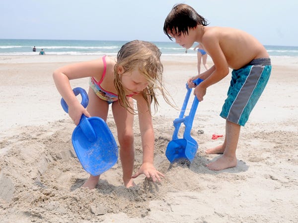 Twin siblings Ava (left) and Amon Tomaro dig a small hole while spending the day at Wrightsville Beach Thursday.