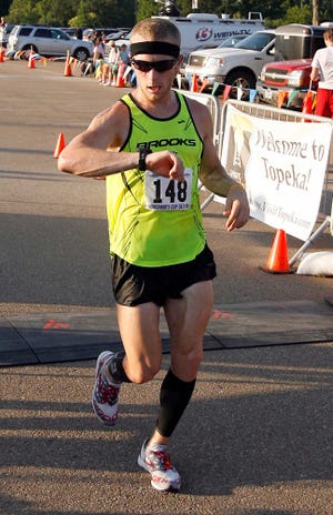 Former Junction City and Pittsburg State runner Tim Testa checks his time as he crosses the finish line in first place in the Sunflower State Games' Governors Cup 10K Friday at Hummer Sports Park.