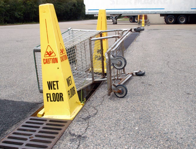 Wet-floor signs and shopping carts temporarily cover where metal grates were stolen from behind Shaw's supermarket on Winthrop Street.