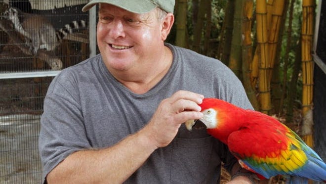 Mark McCarthy with Norma Jean, a scarlett McCaw, at McCarthy's Wildlife Sanctuary in June of 2011.