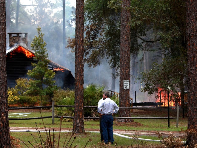 Two men stand and watch the fire at the conference center in the Austin Cary Memorial Forest on Wednesday, July 19, northeast of Gainesville.
