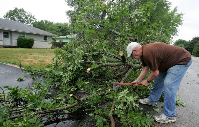 Walter Haight uses an ax to clear a large tree limb from the street and driveway outside his Lawson Drive home in Machesney Park on Monday, July 11, 2011, after a strong storm moved through the Rock River Valley.