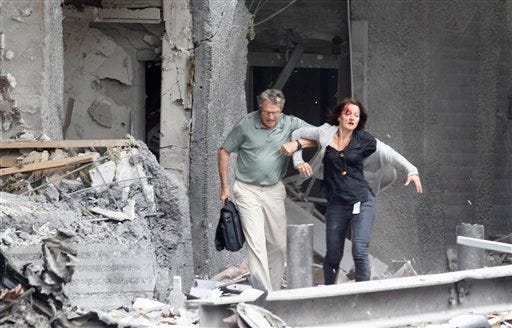 An injured woman is assisted from a damaged building in Oslo on Friday after an explosion rocked the capital.